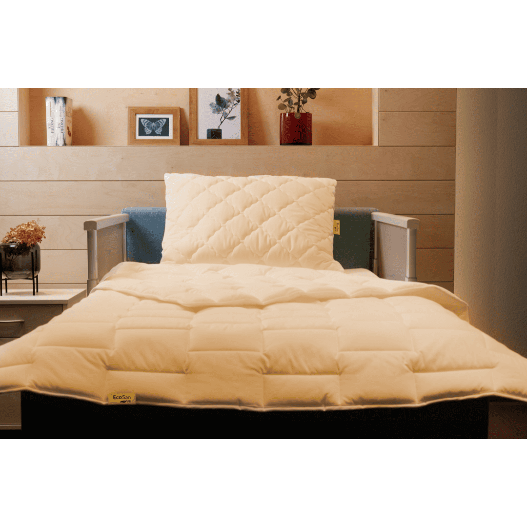 Modern eingerichtetes Bett mit flammhemmendem gestepptem Kopfkissen und hochwertiger Bettdecke.