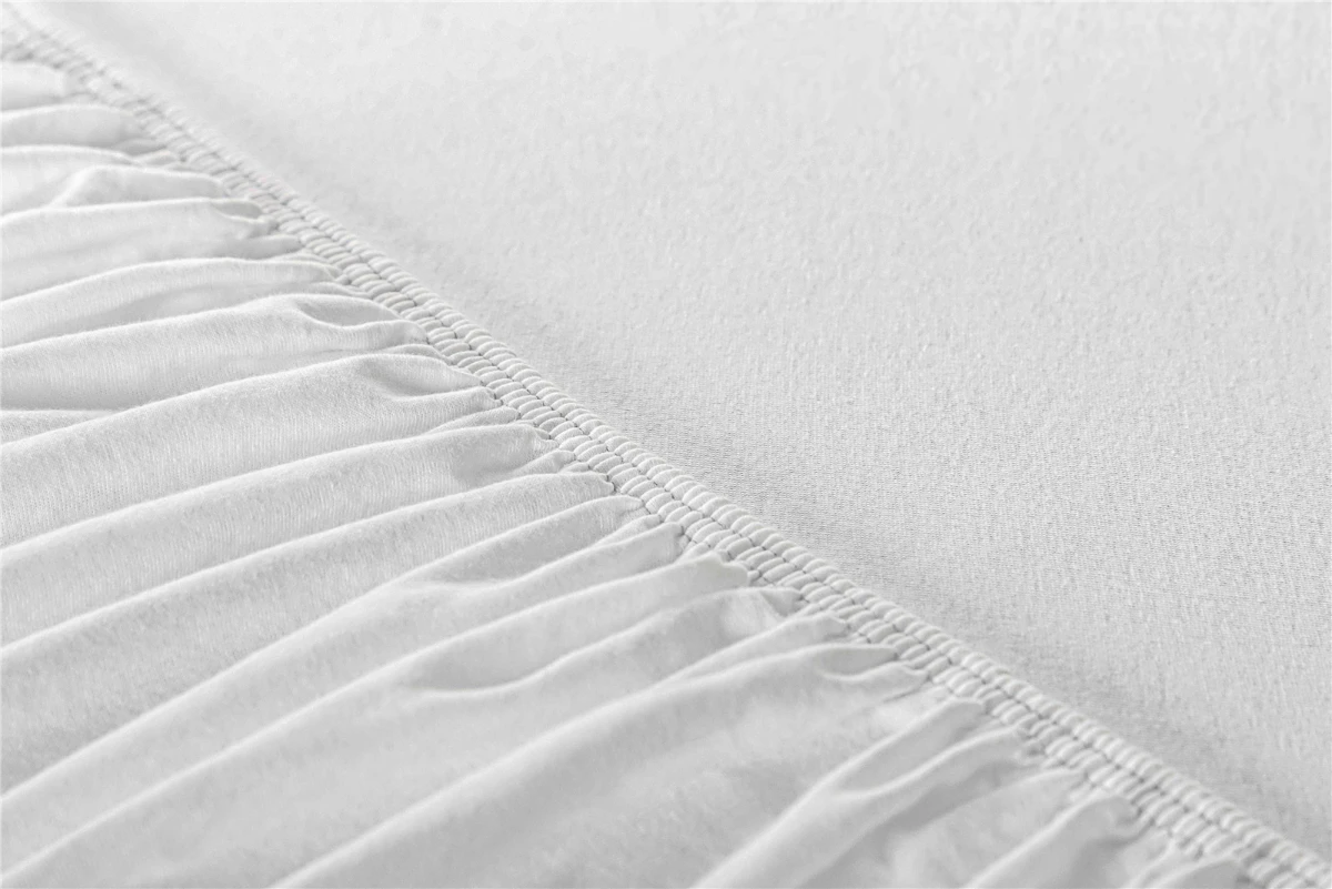 Detailansicht des elastischen Randes eines weißen Spannbettlakens, der für festen Halt sorgt.